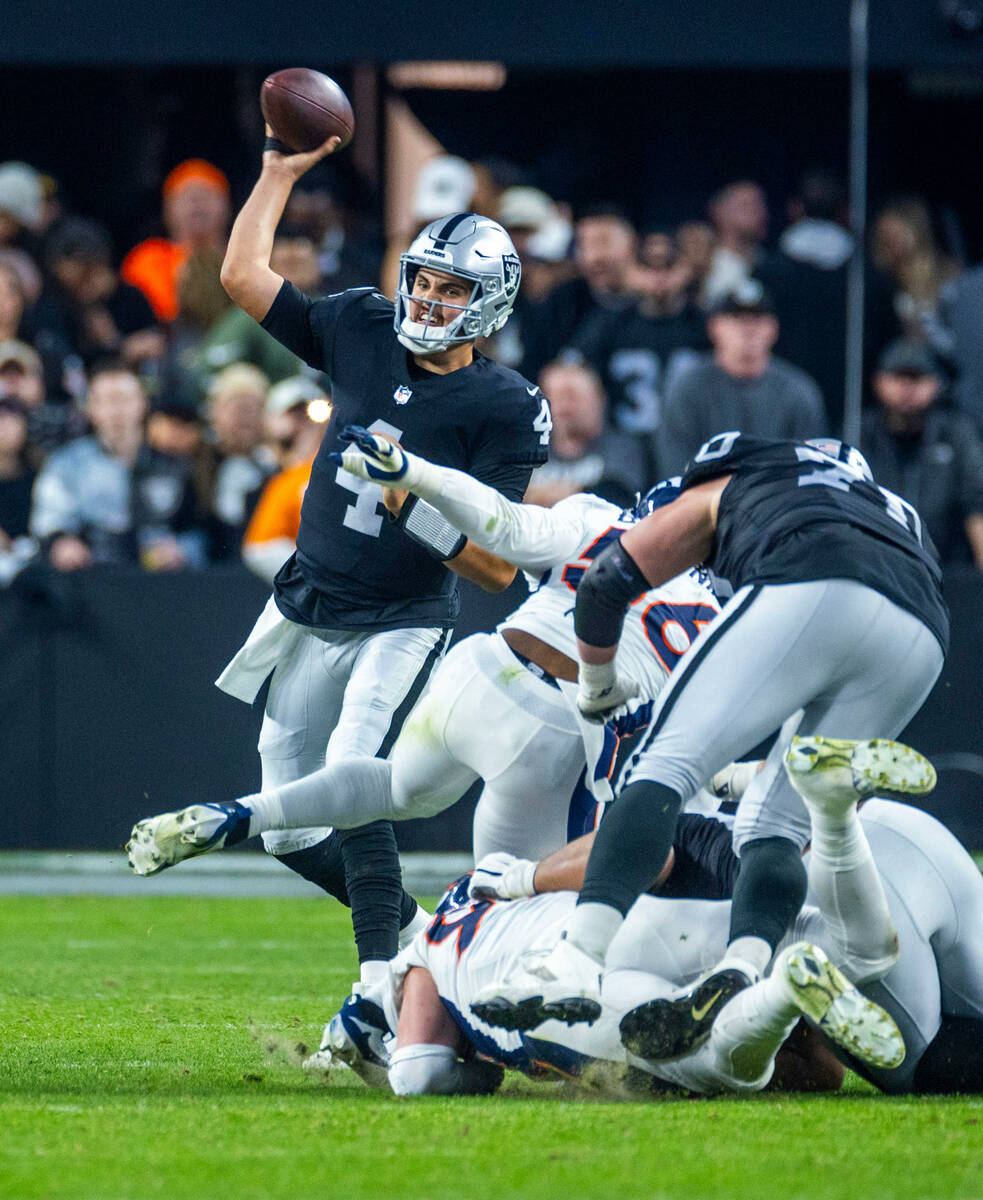 Raiders quarterback Aidan O'Connell (4) gets off a pass under pressure by Denver Broncos lineba ...