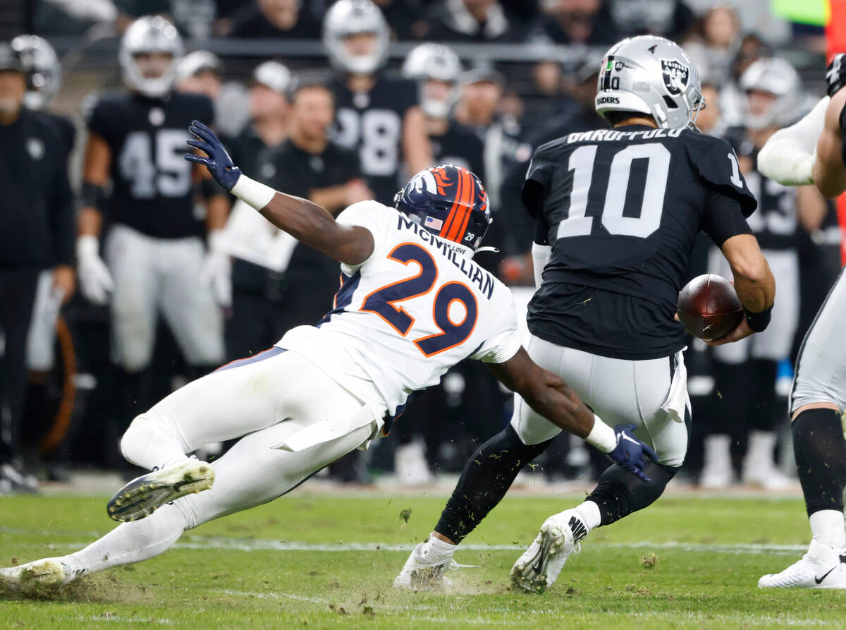 Raiders quarterback Jimmy Garoppolo (10) avoids a tackle from Denver Broncos cornerback Ja'Quan ...