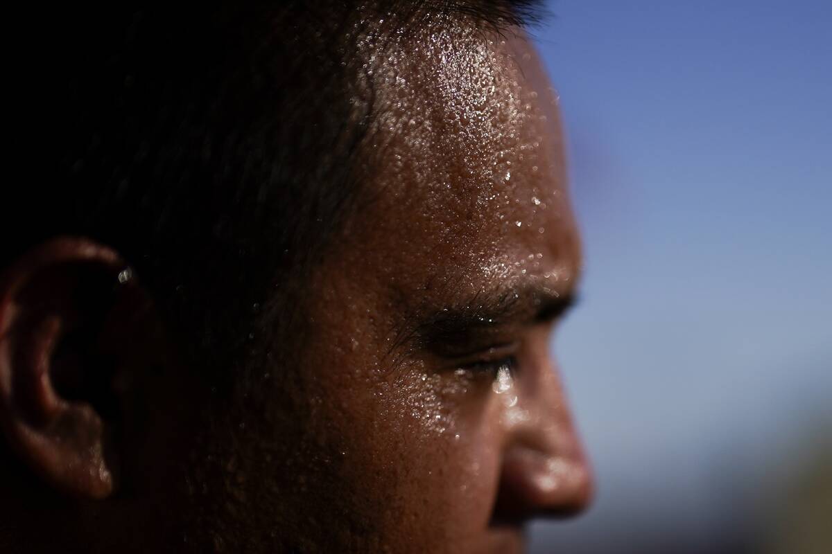 Sweat covers the face of Juan Carlos Biseno after dancing to music from his headphones as after ...