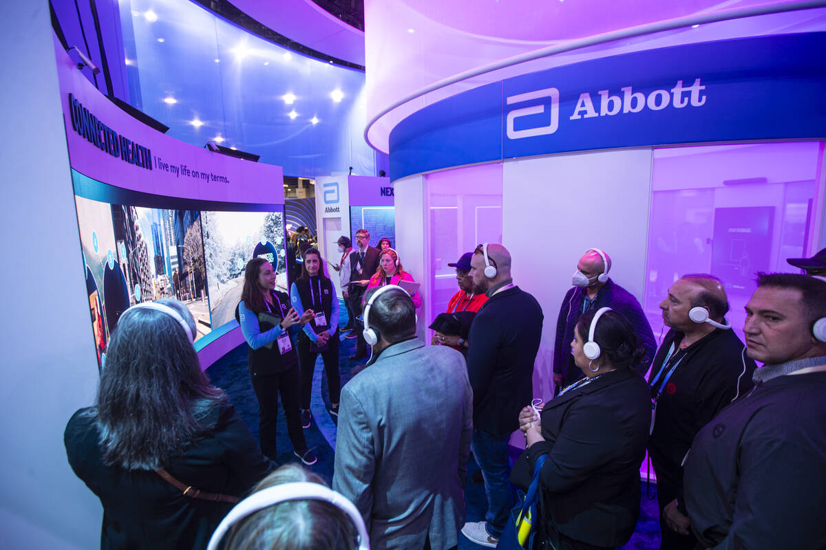 Attendees take a tour of the Abbott booth during the first day of CES at the Las Vegas Conventi ...