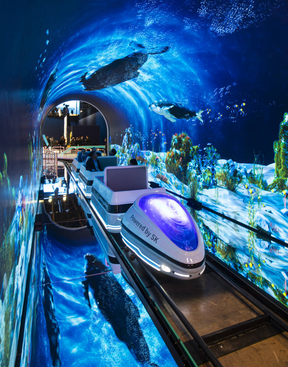 Attendees ride on a hydrogen fuel cell train at the SK Group booth during the first day of CES ...