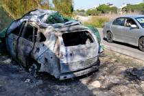 A woman, right, sits in a car and takes pictures of the burned and damaged car that was used by ...