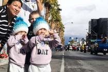 Twin sisters Ava and Anaya Pedraza, 2, make heart shapes with their hands as floats passing by ...