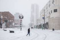 A pedestrian crosses 1st Street SE as snow falls in Cedar Rapids, Iowa, on Tuesday, Jan. 9, 202 ...