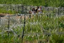 Migrants walk along concertina wire toward Border Patrol officers after illegally crossing the ...