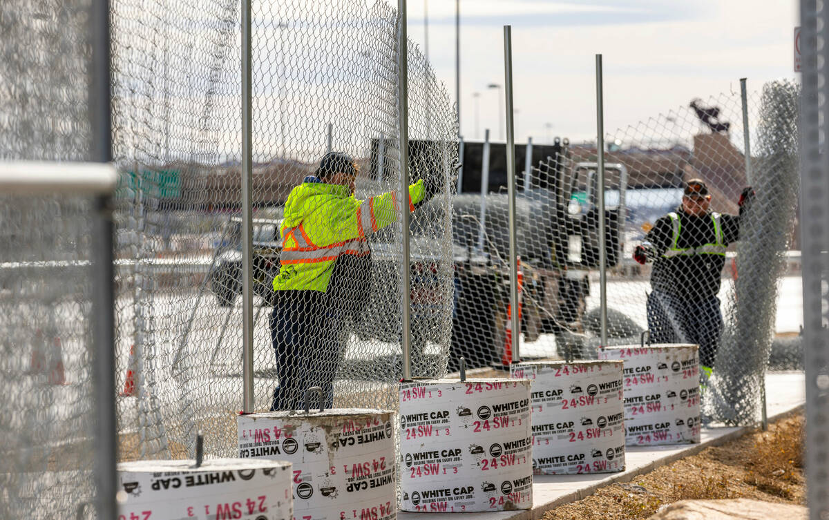 A crew attaches new exterior fence line as Super Bowl preparations continue at Allegiant Stadiu ...