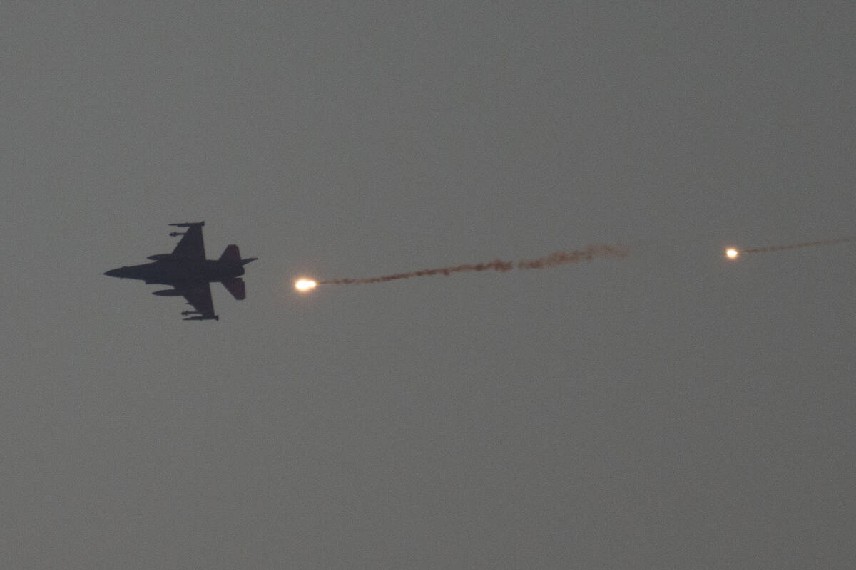 An Israeli fighter jet releases flares as it flies over the Gaza Strip, as seen from southern I ...