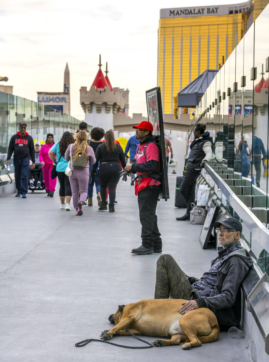 Pedestrians walk along as panhandlers, advertisers and performers occupy spots along the bridge ...