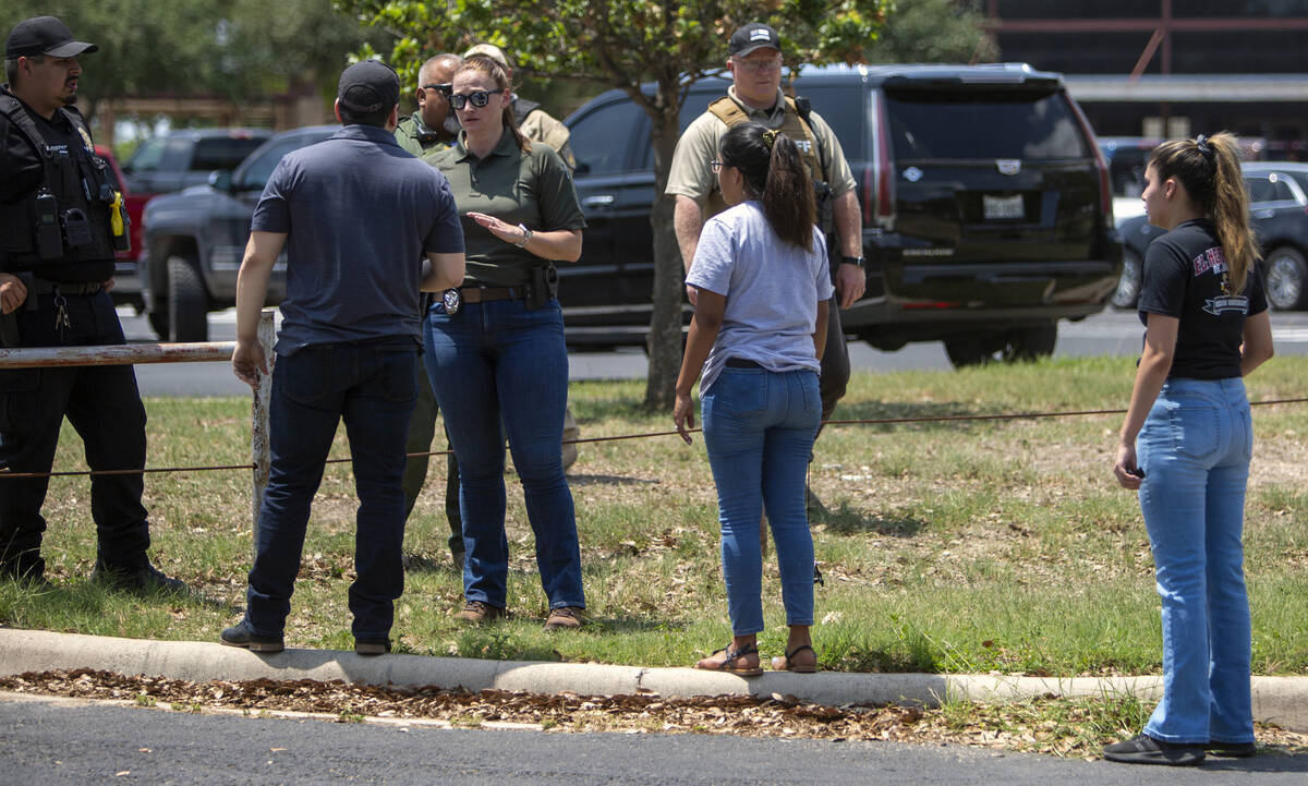 FILE - A law enforcement officer speaks with people outside Uvalde High School after shooting a ...