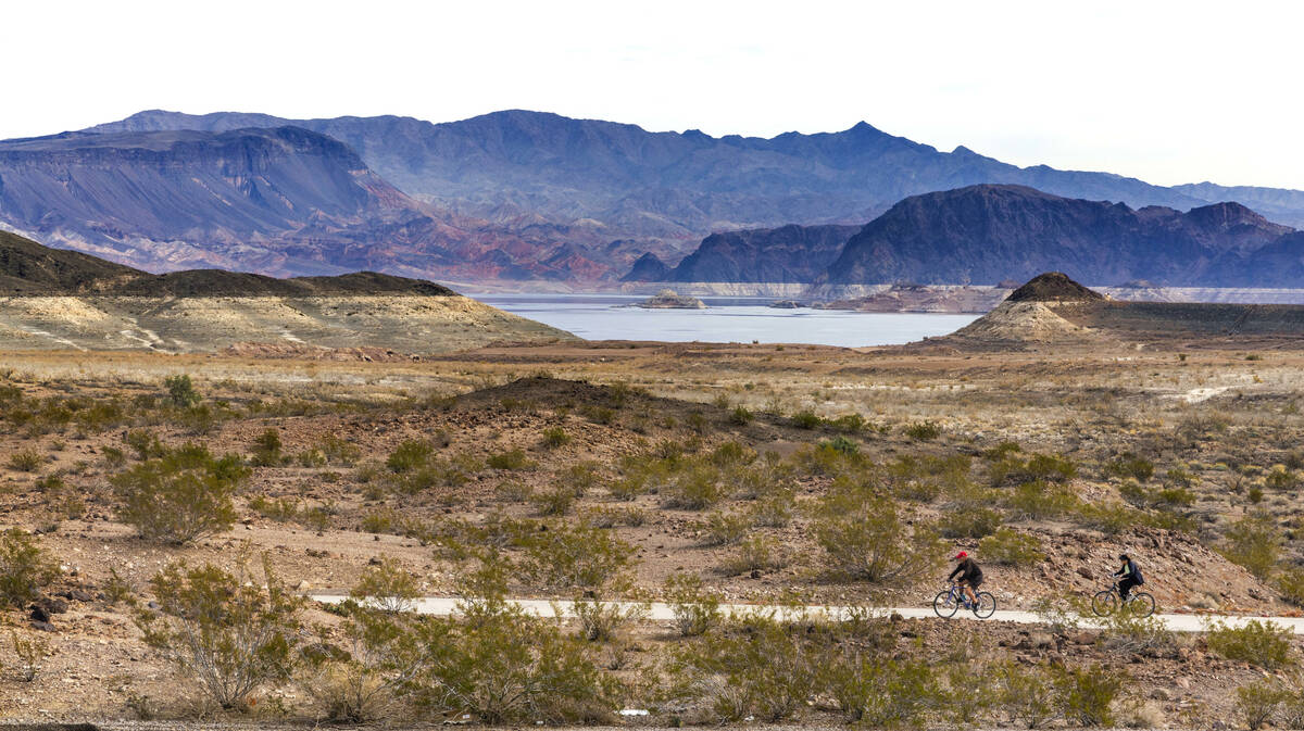 Cyclist ride along the River Mountains Loop Trail with the rising shoreline in the distance aft ...