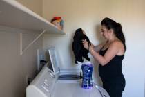 Alexis Cossman puts her work clothes into the washing machine on Wednesday, July 15, 2020, in L ...
