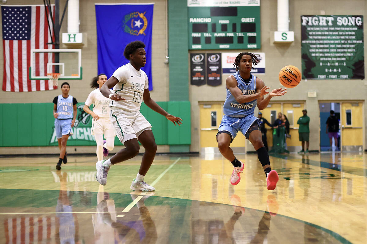 Canyon Springs guard Emanuel Custard passes while Rancho guard Ahmad Koroma (13) catches up to ...