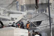 Emergency services work at a building hit by an air strike in Damascus, Syria, Saturday, Jan. 2 ...
