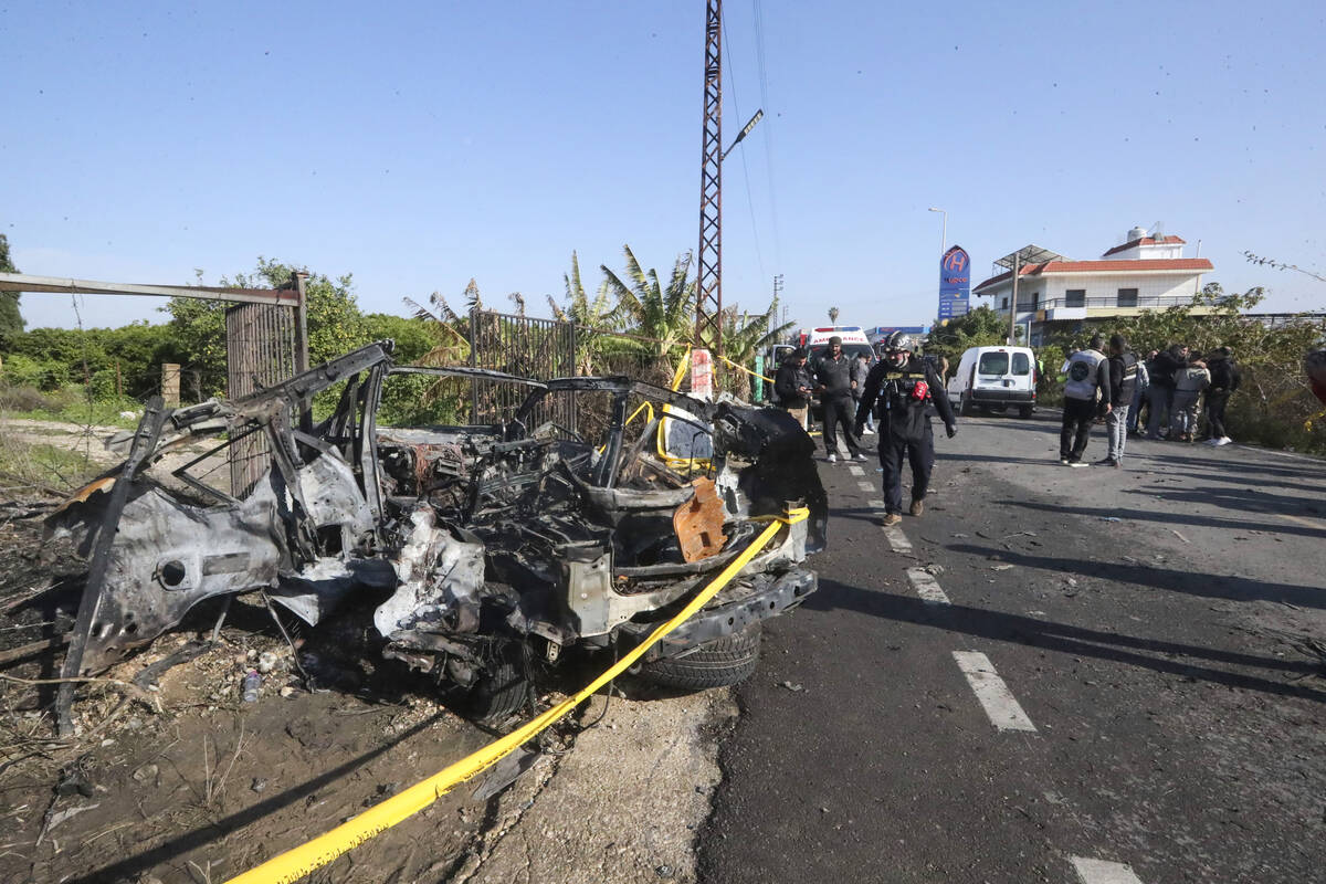 Civil defense worker searches a damaged car in the southern town of Bazouriyeh, Lebanon, Saturd ...