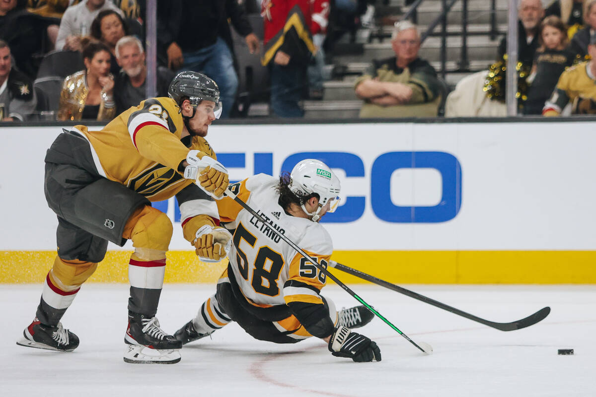 Golden Knights center Brett Howden (21) reaches for the puck over Pittsburgh Penguins defensema ...