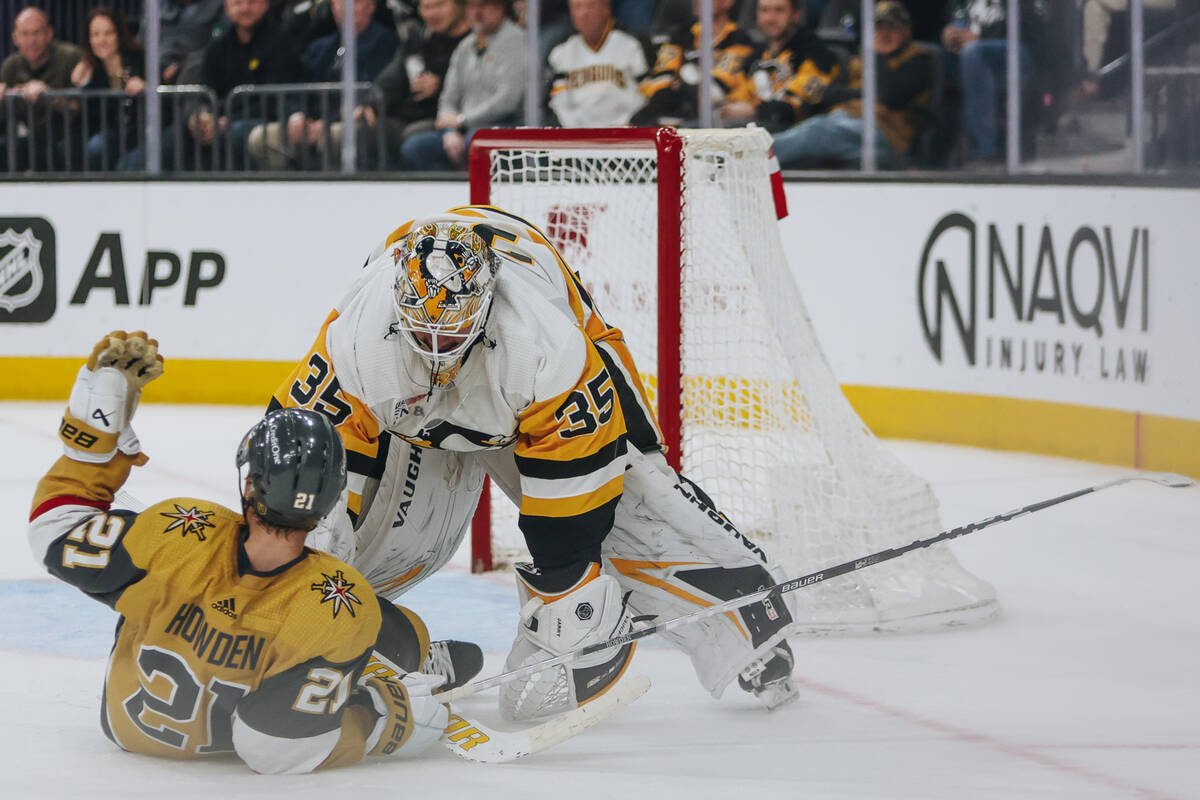 Golden Knights center Brett Howden (21) trips over Pittsburgh Penguins goaltender Tristan Jarry ...