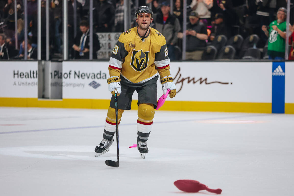 Golden Knights defenseman Alec Martinez (23) picks up plastic flamingo toys off of the ice afte ...