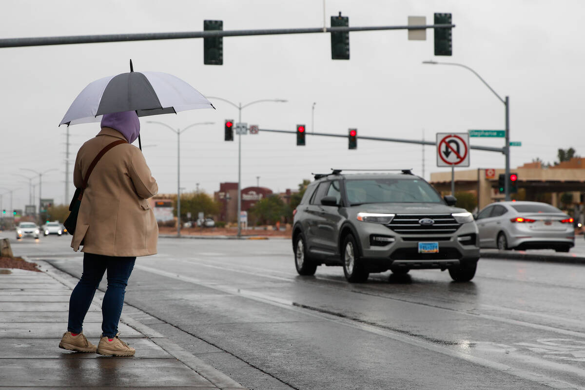 A person holding an umbrella braves through the rain during a winter storm on Monday, Jan. 22, ...