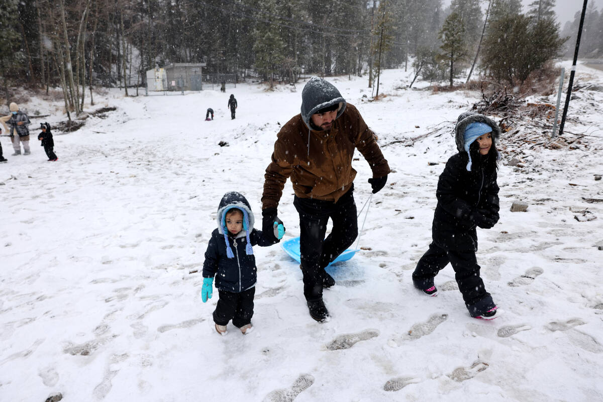 Jonnathan Cabrera walks through the snow with his daughters Riley, 3, and Natalie, 8, off the s ...