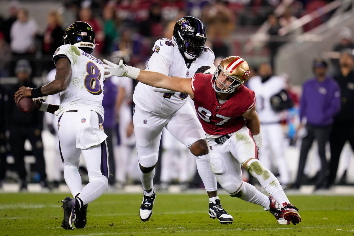 Baltimore Ravens quarterback Lamar Jackson, left, escapes pressure from San Francisco 49ers def ...