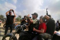 FILE - Palestinians transport a captured Israeli civilian, Adina Moshe, from her home in Kibbut ...