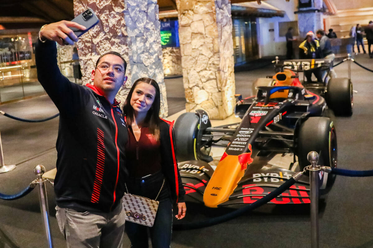 Strip tourists pose for a picture in front of a Red Bull Racing Formula 1 race car prior to the ...