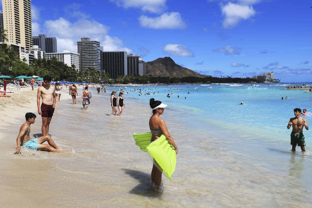 Beachgoers take to the waves on Waikiki Beach in Honolulu, where eight Clark County School Dist ...