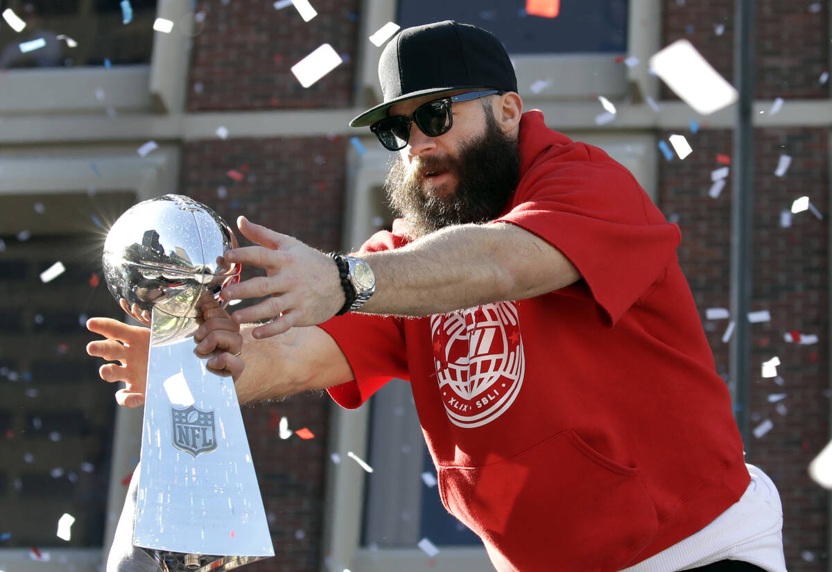 New England Patriots' Julian Edelman reaches for a Super Bowl trophy during their victory parad ...