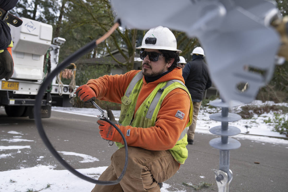 File - A worker from Portland General Electric replaces a power line as crews work to restore p ...