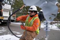 File - A worker from Portland General Electric replaces a power line as crews work to restore p ...