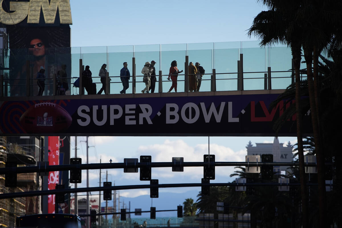 People walk across a pedestrian walkway along the Las Vegas Strip ahead of the Super Bowl 58 fo ...