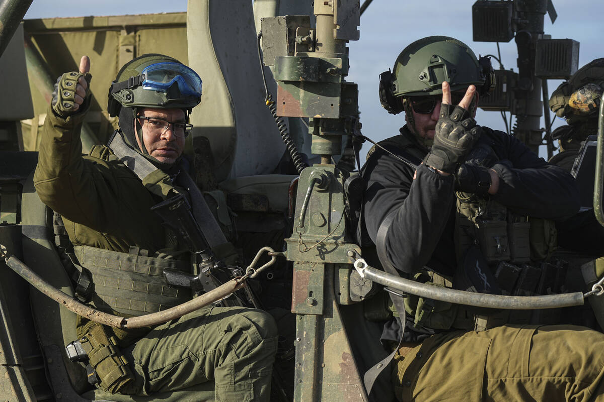 Israeli soldiers wave from their vehicle on the way back from the Gaza Strip, in southern Israe ...