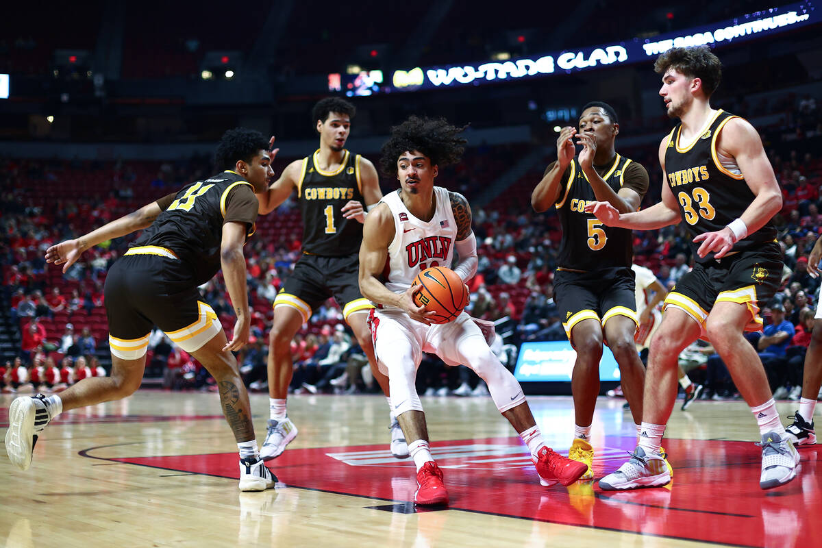 UNLV Rebels guard Brooklyn Hicks (13) pivots to pass while surrounded by the Wyoming Cowboys du ...