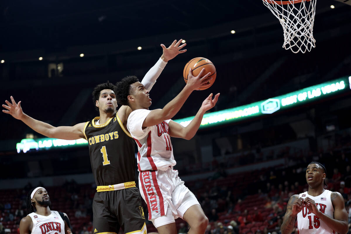 UNLV Rebels guard Dedan Thomas Jr. (11) shoots against Wyoming Cowboys guard Brendan Wenzel (1) ...