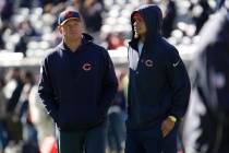 Injured Chicago Bears quarterback Justin Fields, right, stands on the field with offensive coor ...