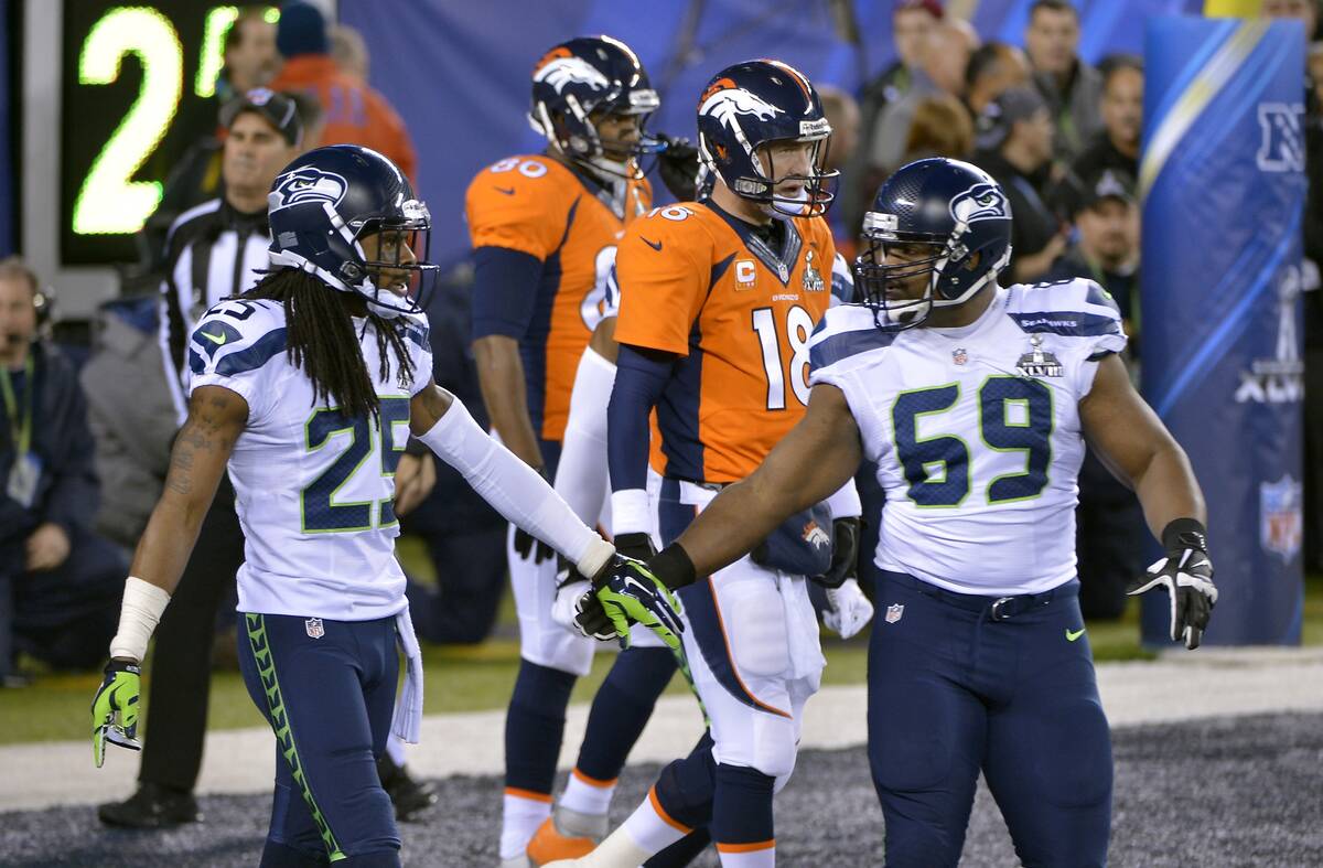 Seattle Seahawks' Richard Sherman, left, and Clinton McDonald, right, react in front of Denver ...