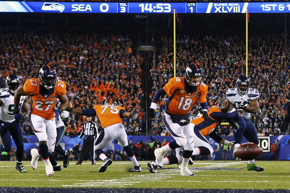 The football is snapped over Denver Broncos quarterback Peyton Mannings head on the first play ...