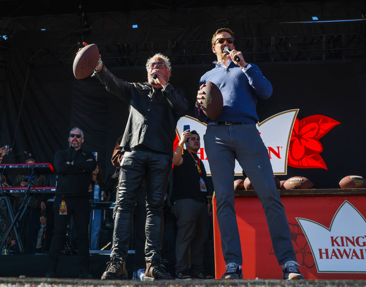 Guy Fieri, left, and Eli Manning, right, address the crowd before throwing signed footballs to ...