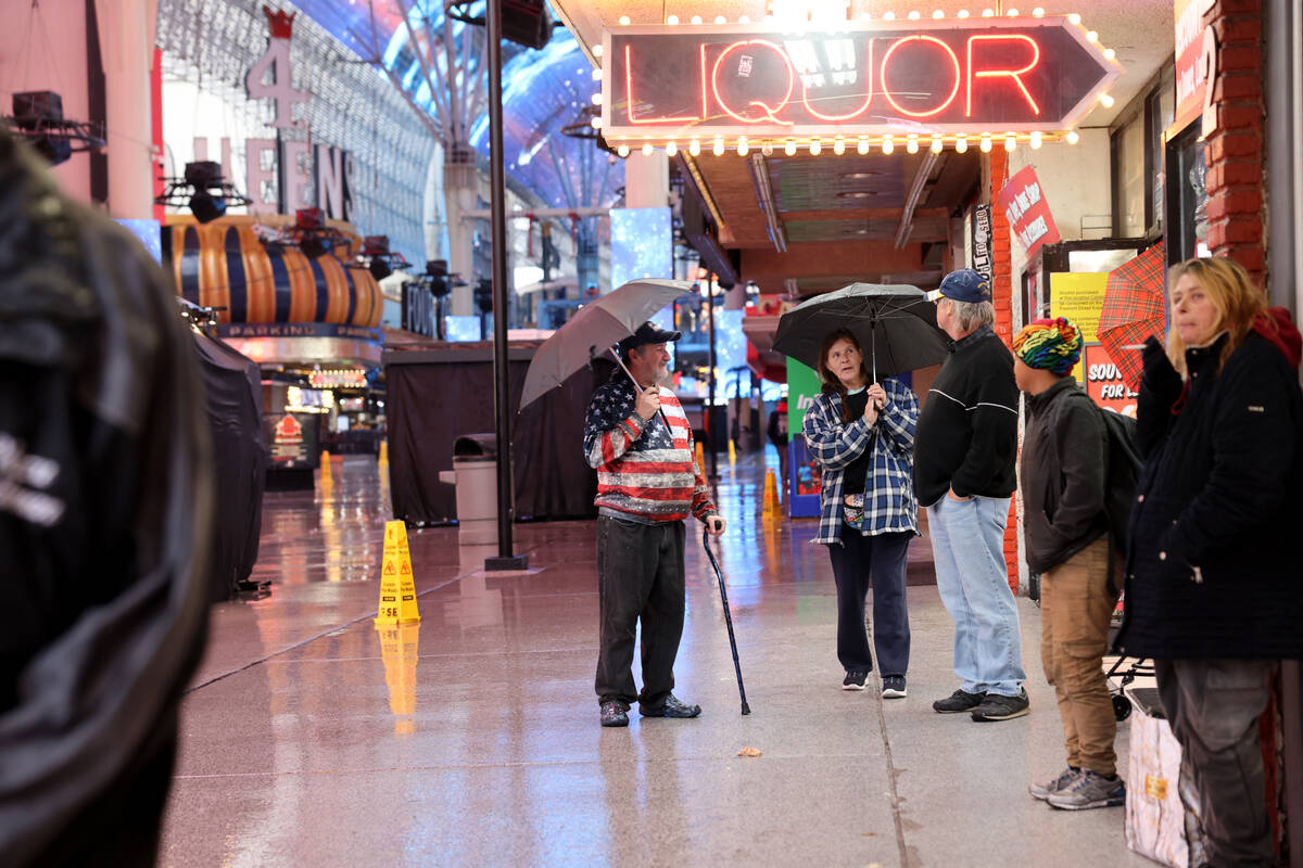 People buy new umbrellas during a light rain at the Fremont Street Experience in downtown Las V ...