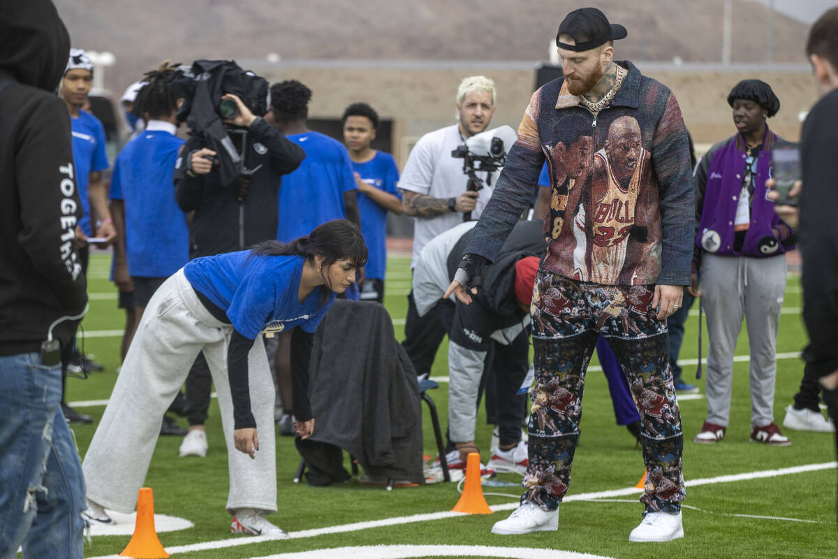 Raiders defensive end Maxx Crosby, right, works with a participant of the Field the Future Madd ...