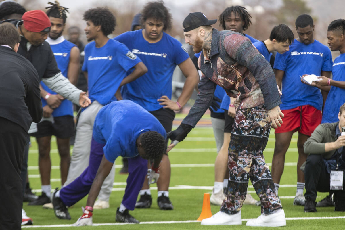 Raiders defensive end Maxx Crosby, right, works with a participant of the Field the Future Madd ...
