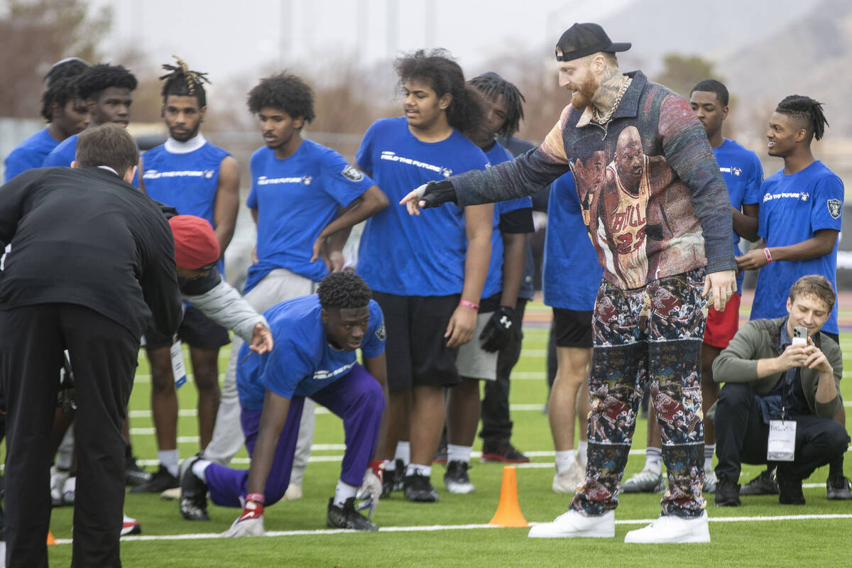 Raiders defensive end Maxx Crosby, right, works with a participant of the Field the Future Madd ...
