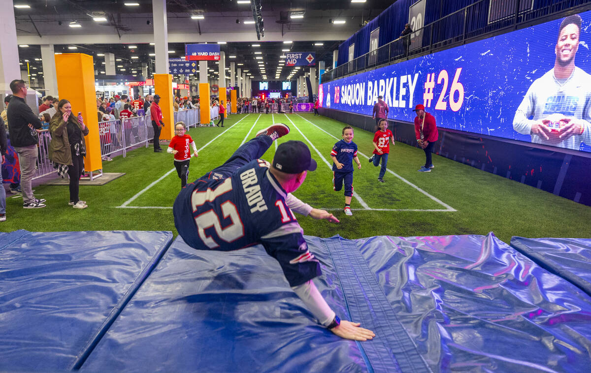 A fan beats his kids on the 40-yard dash leaping onto crash mats at the end of the race during ...