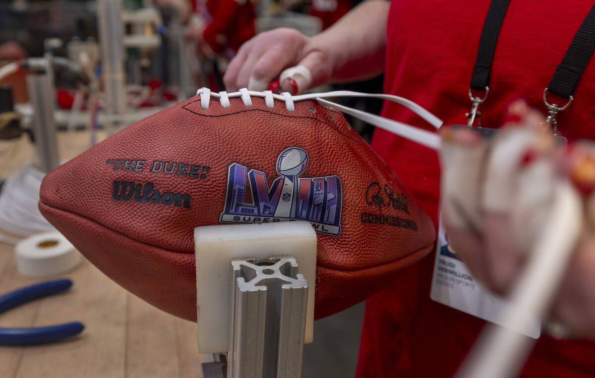 Trudi Vermillion with Wilson hand laces a new football in their football making display space d ...