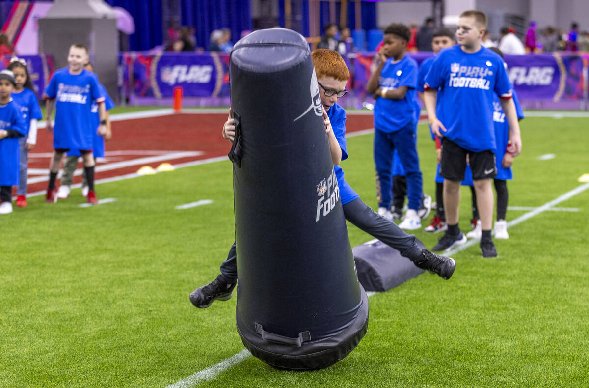 A young fan tackles a dummy during a skills training session at the Super Bowl Experience at th ...