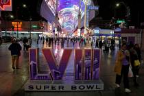 People walk past a sign for Super Bowl 58 at the Fremont Street Experience Tuesday, Feb. 6, 202 ...