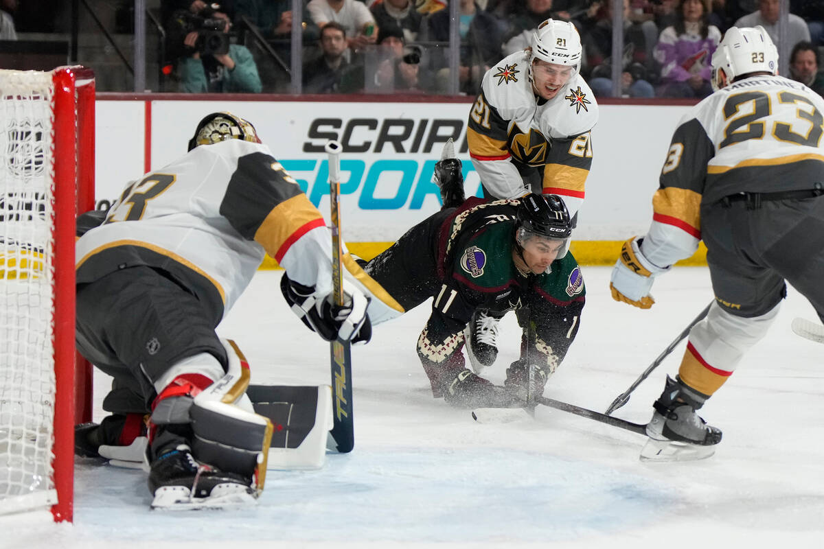 Vegas Golden Knights center Brett Howden (21) checks Arizona Coyotes right wing Dylan Guenther ...