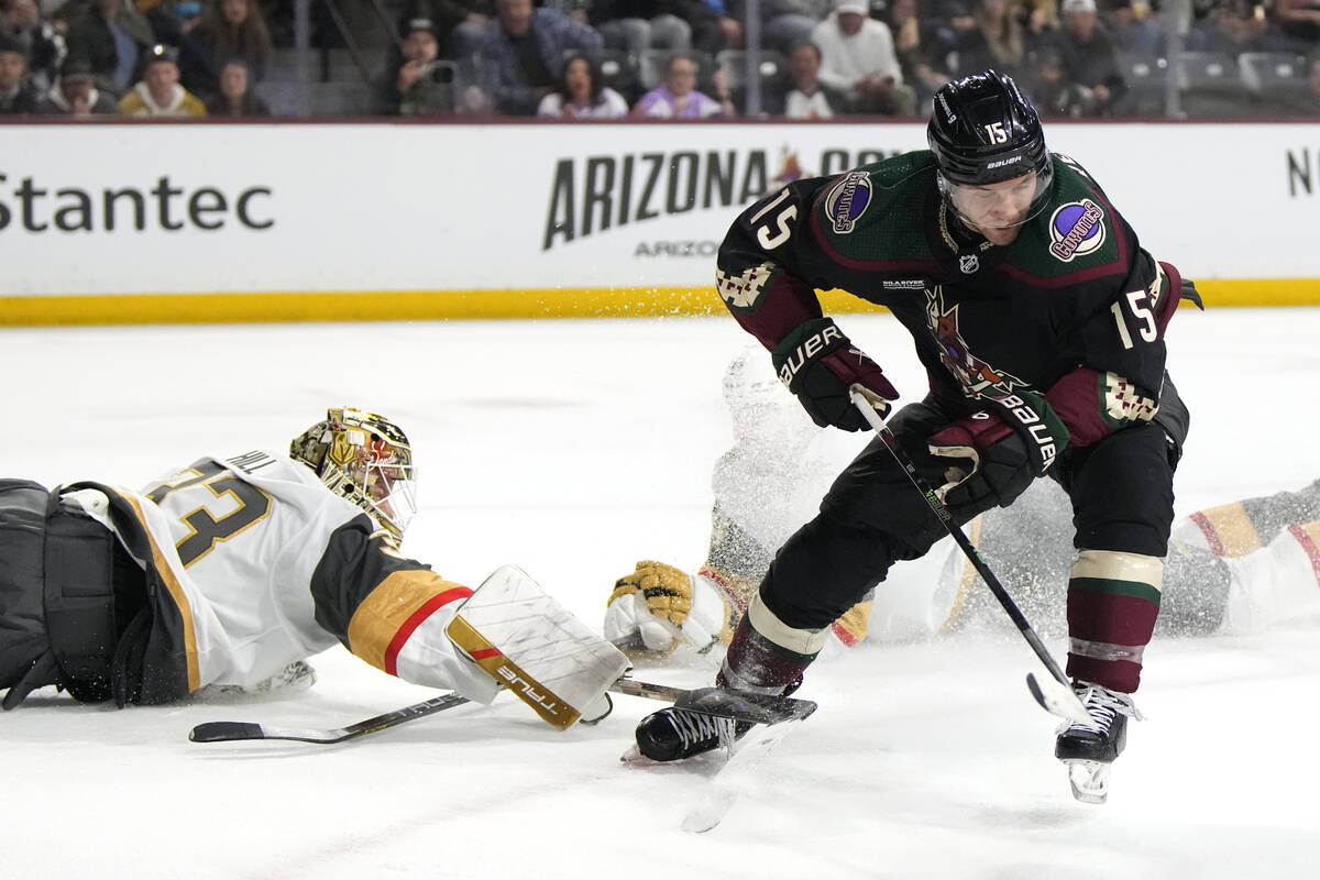 Vegas Golden Knights goaltender Adin Hill knocks the puck away from Arizona Coyotes center Alex ...