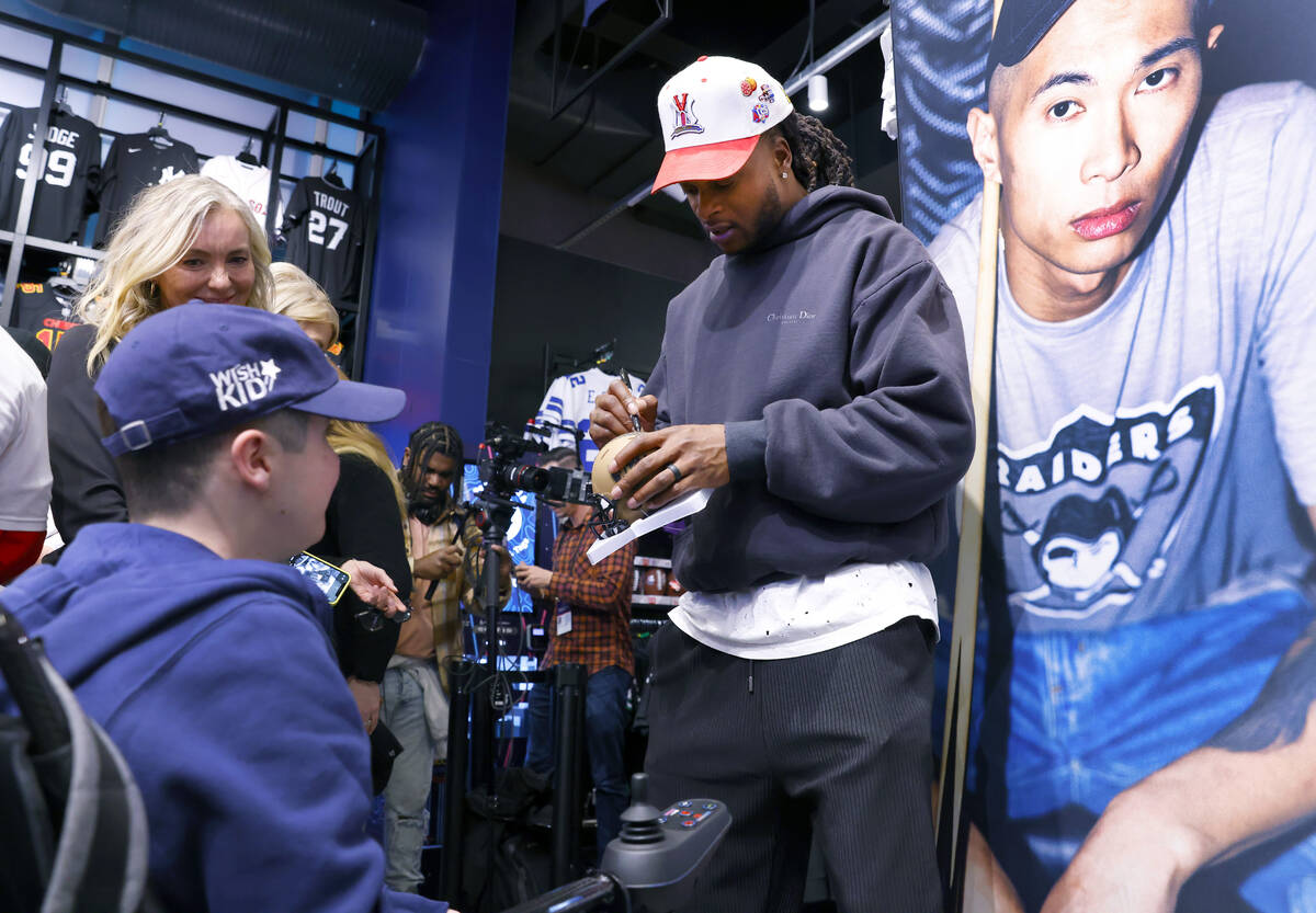 Raiders wide receiver Davante Adams signs an autograph to Ryan Schultz at the Lids Flagship Sto ...