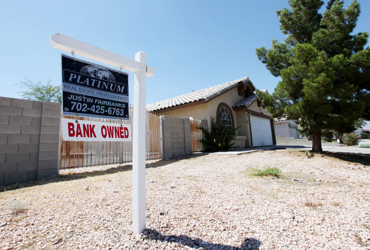 A real estate sign with a "bank owned" tag attached hangs in front of a house on Wednesday, Jun ...